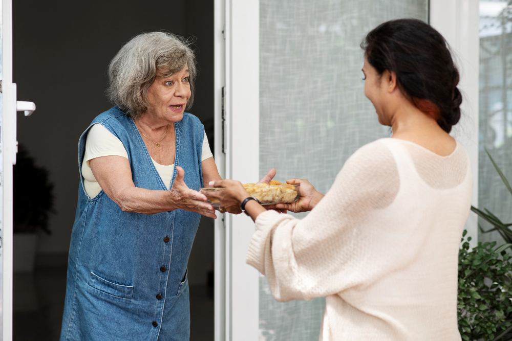 Une femme offrant un repas à une personne âgée